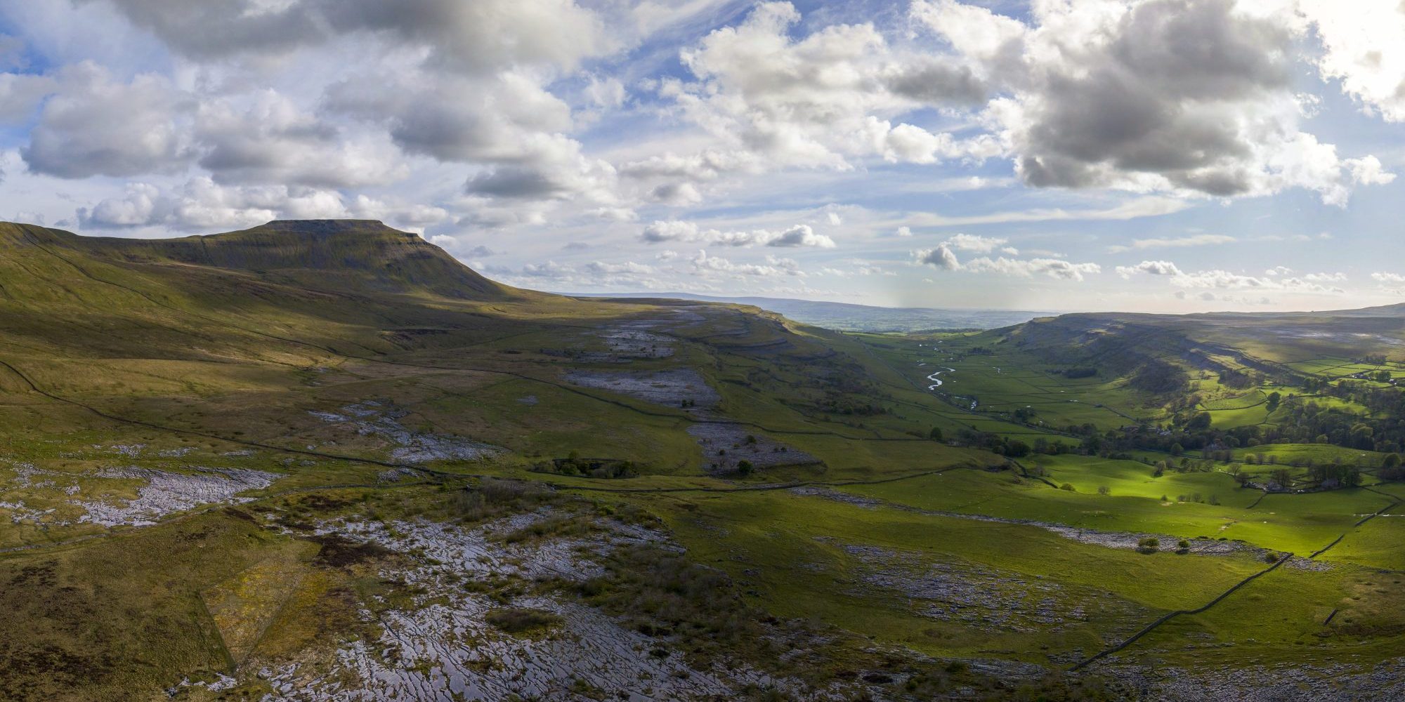Drone panoramic of grass and limestone pavement in the foreground and Ingleborough mountain in the background